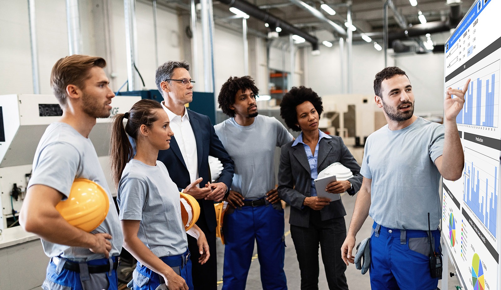 Opérateurs d'une industrie échangeant devant un écran du logiciel MES Qubes.